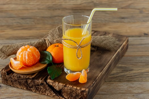 Glass of fresh tangerine juice with ripe tangerines on wooden board photo