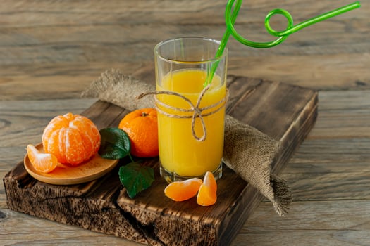 Glass of fresh tangerine juice with ripe tangerines on wooden board photo