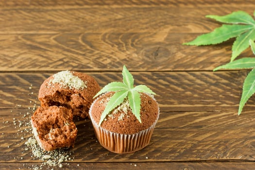 Healthy and tasty vegan and gluten free muffins topped with hemp seeds on a white plate on wooden table. Marijuana cupcake muffins with cannabis leaves photo