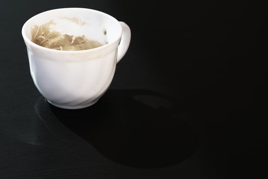 Empty little glass cup from coffee with milk, dirty used small ceramic mug from cappuccino, white finished tiny bowl from expresso isolated on the black tabletop, nobody cafe dishware, closeup, art. photo