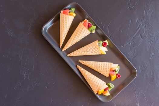 waffle cones with fresh fruit on a black tray. top view. delicious dessert. photo