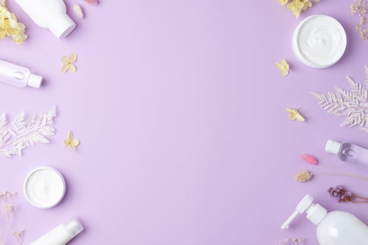 Cosmetic skin care products with flowers on rose background. Flat lay, copy space photo