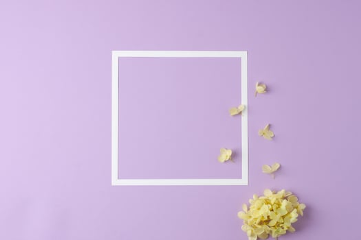 Cosmetic background with flowers and white frame on rose. Flat lay, copy space photo
