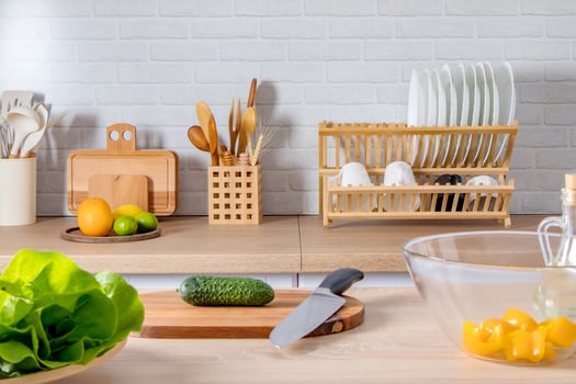 front view of the kitchen table and countertop with ingredients for preparing a vegetable salad. dish with fresh vegetables, cutting board, spices. photo