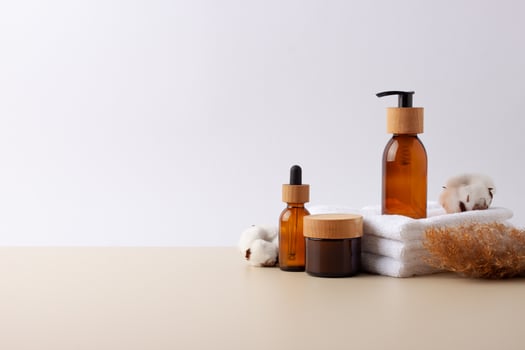 Spa treatment with natural skin care products, towel and flowers on white background. Close up, copy space photo