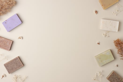 Soap and flower on beige background. Flat lay, copy space. photo