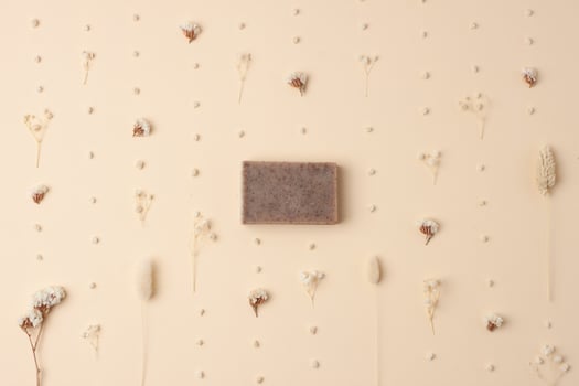 Soap and flower on beige background. Flat lay, copy space. photo