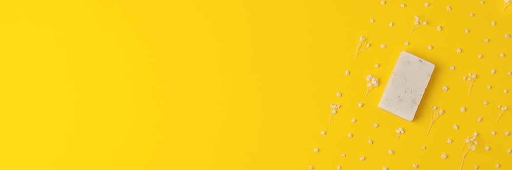 Soap and flower on yellow background. Flat lay, copy space. photo