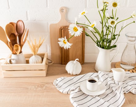 stylish decor of a modern kitchen. various items of kitchen utensils on a wooden countertop. front view. jug of daisies. photo
