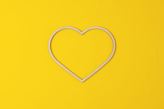 Cosmetic background with a wooden heart on yellow. Flat lay, copy space photo