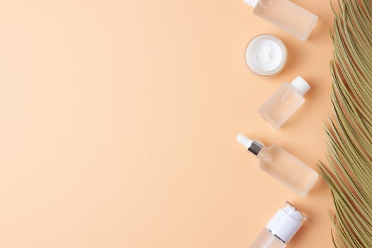 Cosmetic skin care products with palm leaf on pastel beige background. Flat lay, copy space photo