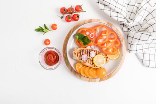 homemade chicken breast steak with fresh vegetables on a plate standing on a wooden round tray. sauce or ketchup to improve the taste. top view. photo
