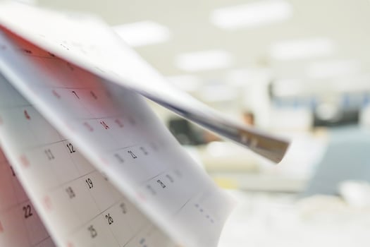 Calendar page flipping sheet on table with blurred office interior background business schedule planning appointment meeting concept photo