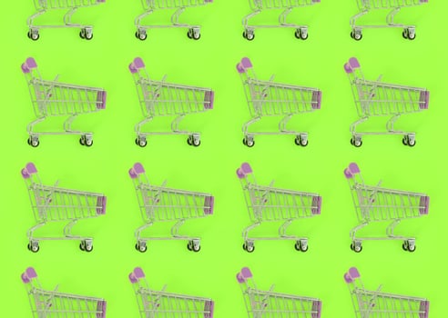 Shopping addiction, shopping lover or shopaholic concept. Many small empty shopping carts perform a pattern on a pastel colored paper background. Flat lay composition, top view photo