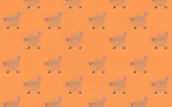 Shopping addiction, shopping lover or shopaholic concept. Many small empty shopping carts perform a pattern on a pastel colored paper background. Flat lay composition, top view photo