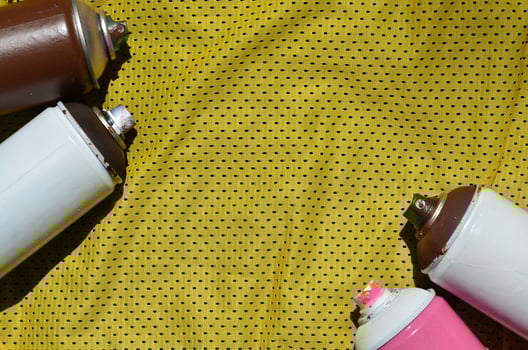 Several used aerosol paint sprayers lie on the sports shirt of a basketball player made of polyester fabric. The concept of youth street art, active sports and eventful lifestyle photo