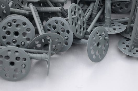 Background of many gray plastic dowels fastening for thermal insulation. A huge pile of plastic bolts with round holey hats lies on a gray foam polystyrene plate photo