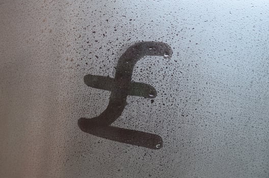 Symbol of English pounds is written with a finger on the surface of the misted glass photo