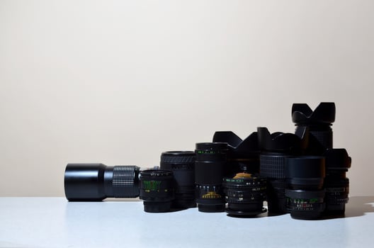 Many different professional lenses for SLR camera lies on a colorless desk photo