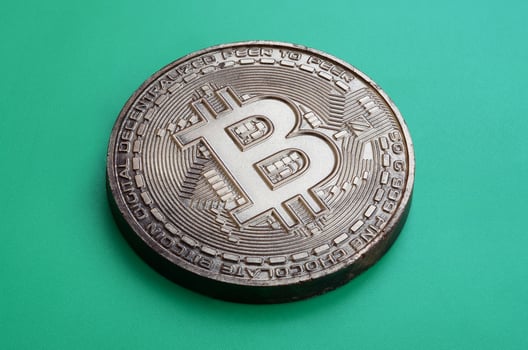 Chocolate product in the form of physical bitcoin lies on a green plastic background. Model of the crypto currency in the edible form photo
