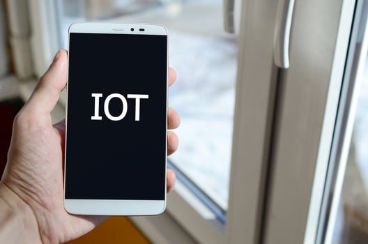 A person sees a white inscription on a black smartphone display that holds in his hand. IOT photo