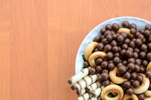 Crispy tubules, chocolate melting balls and bagels lie in a white plate on a wooden table. Mix of various sweets photo