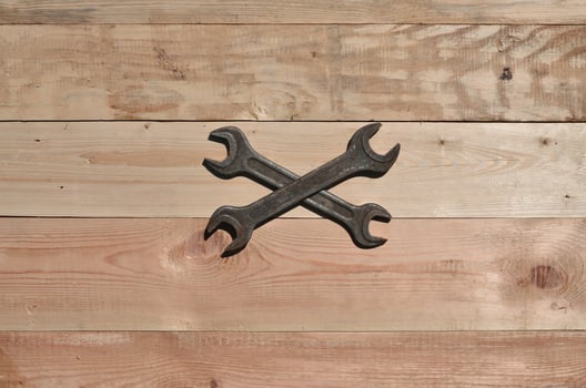 A few rusty spanners lies on a wooden table in a workshop photo
