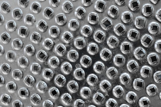 A fragment of a metal chrome grater close-up. Texture of blades for grinding food photo