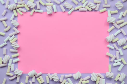 Colorful marshmallow laid out on violet and pink paper background. pastel creative textured framework. minimal photo