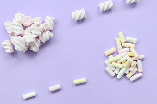 Colorful marshmallow laid out on violet paper background. pastel creative texture. minimal photo