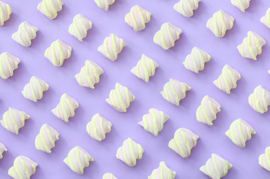 Colorful marshmallow laid out on violet paper background. pastel creative textured pattern. minimal photo