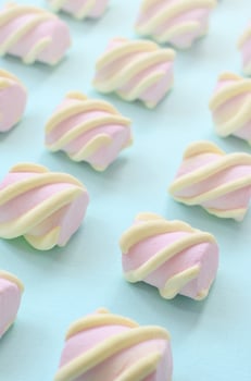 Colorful marshmallow laid out on blue paper background. pastel creative textured pattern. Perspective macro shot photo