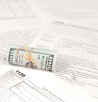 1120 U.S. Corporation income tax return form with roll of american dollar banknotes photo