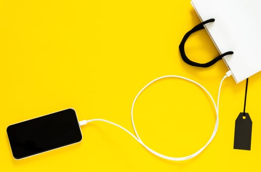 Shopping online from smartphone connect with charger wire to shopping bag. Cyber Monday and Black Friday concept. photo