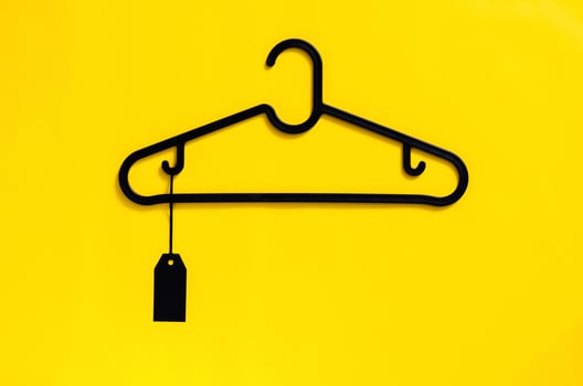 A black hanger with blank black price tag on yellow background. Black Friday concept. photo