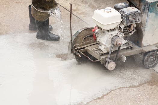 Worker using diamond saw blade machine cutting concrete road at construction site photo