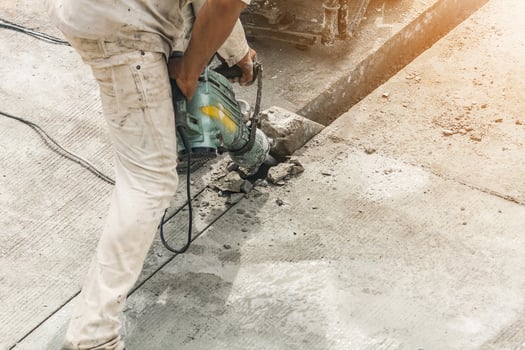 Construction worker using jackhammer drilling concrete surface photo