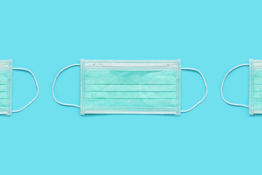 Surgical face mask on blue background protection against COVID-19 coronavirus. Healthcare and medical concept photo