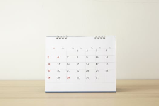 Calendar page close up on wood table with white wall background business planning appointment meeting concept photo