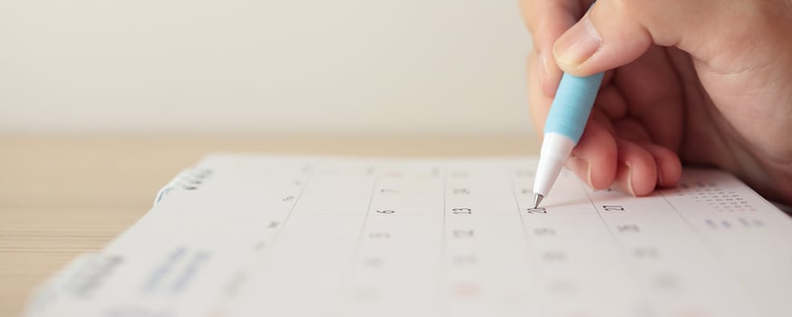 Hand with pen writing on calendar date photo
