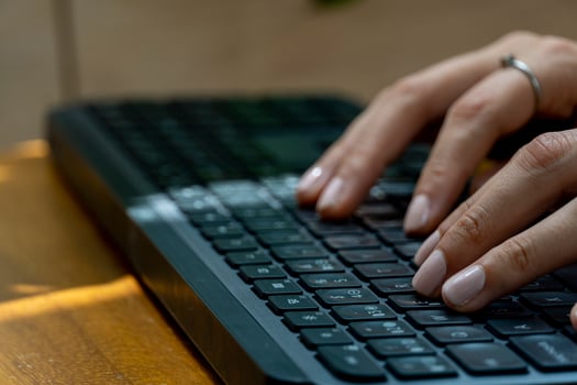 young mexican latina woman, typing on a wireless keyboard on her computer photo