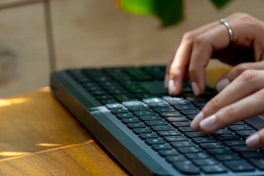 young mexican latina woman, typing on a wireless keyboard on her computer photo