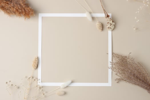 White frame with flovers on beige background. Flat lay, copy space. photo