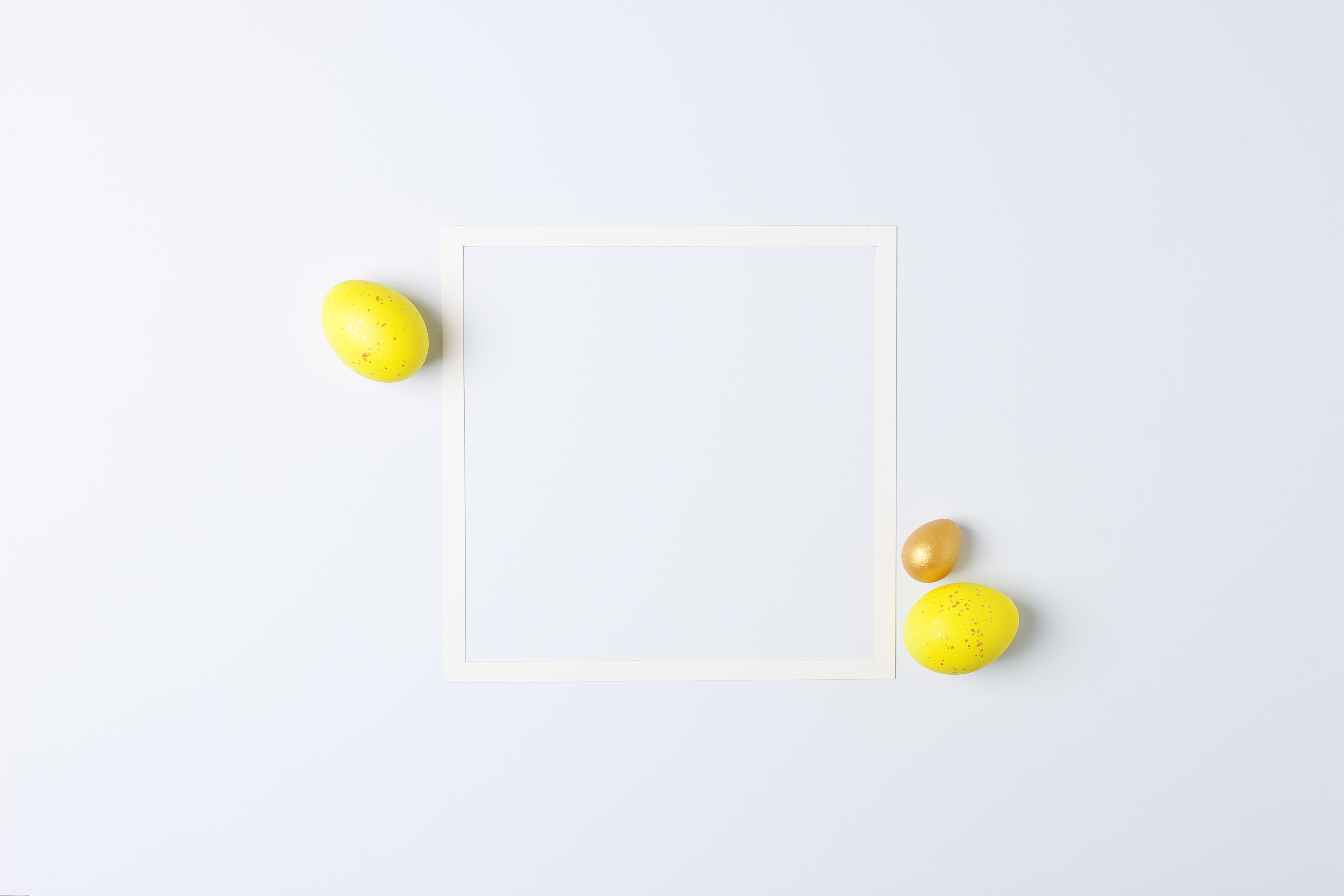 Easter yellow eggs with white frame on white background. Flat lay, copy space. photo