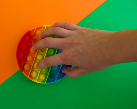 Pop it toy on a green and orange background, a person's hand photo