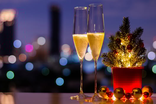 Two glasses of sparkling wine with Christmas tree and bauble ornaments put on table with colorful city bokeh lights background. photo