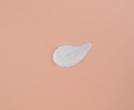 White smear of cosmetic cream on a beige background. Creamy foundation texture isolated. Smear of face cream. Close up of cream texture photo