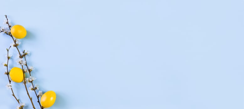 Banner of colorful Easter eggs with spring flowering flowers, on a blue background. Holiday border of colored eggs. Space for text. photo