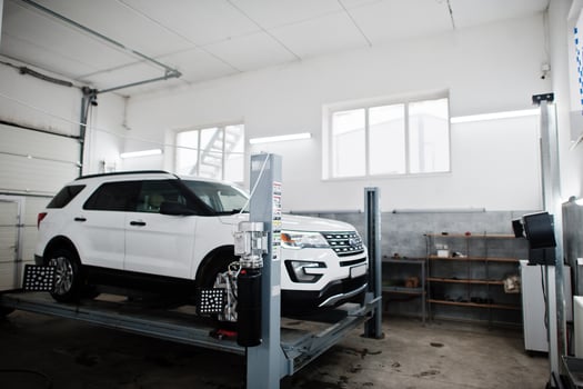 American SUV car on stand for wheels alignment camber check in workshop of service station. photo