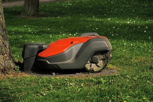 Robotic Lawn Mower on green grass background.Automatic robot lawnmower in modern garden.Green grass trimming with lawn mower. Close-up view of the lawn mower dirty blade after mowing the lawn. photo